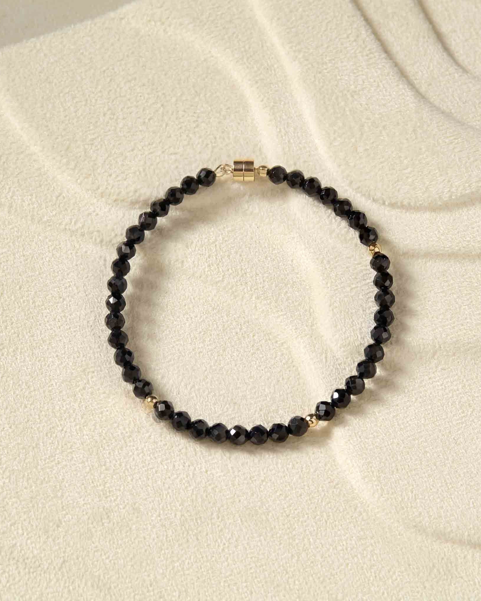 Black beaded bracelet on a beige fabric background