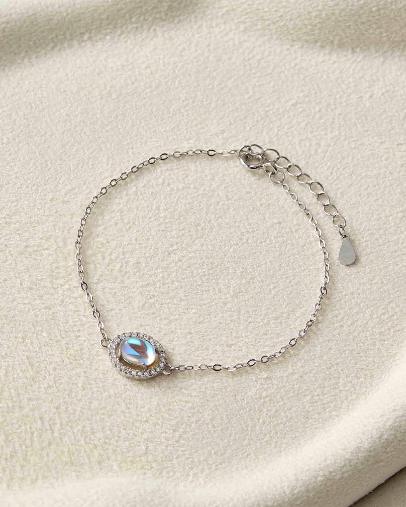 Silver bracelet with a gemstone on a beige fabric background