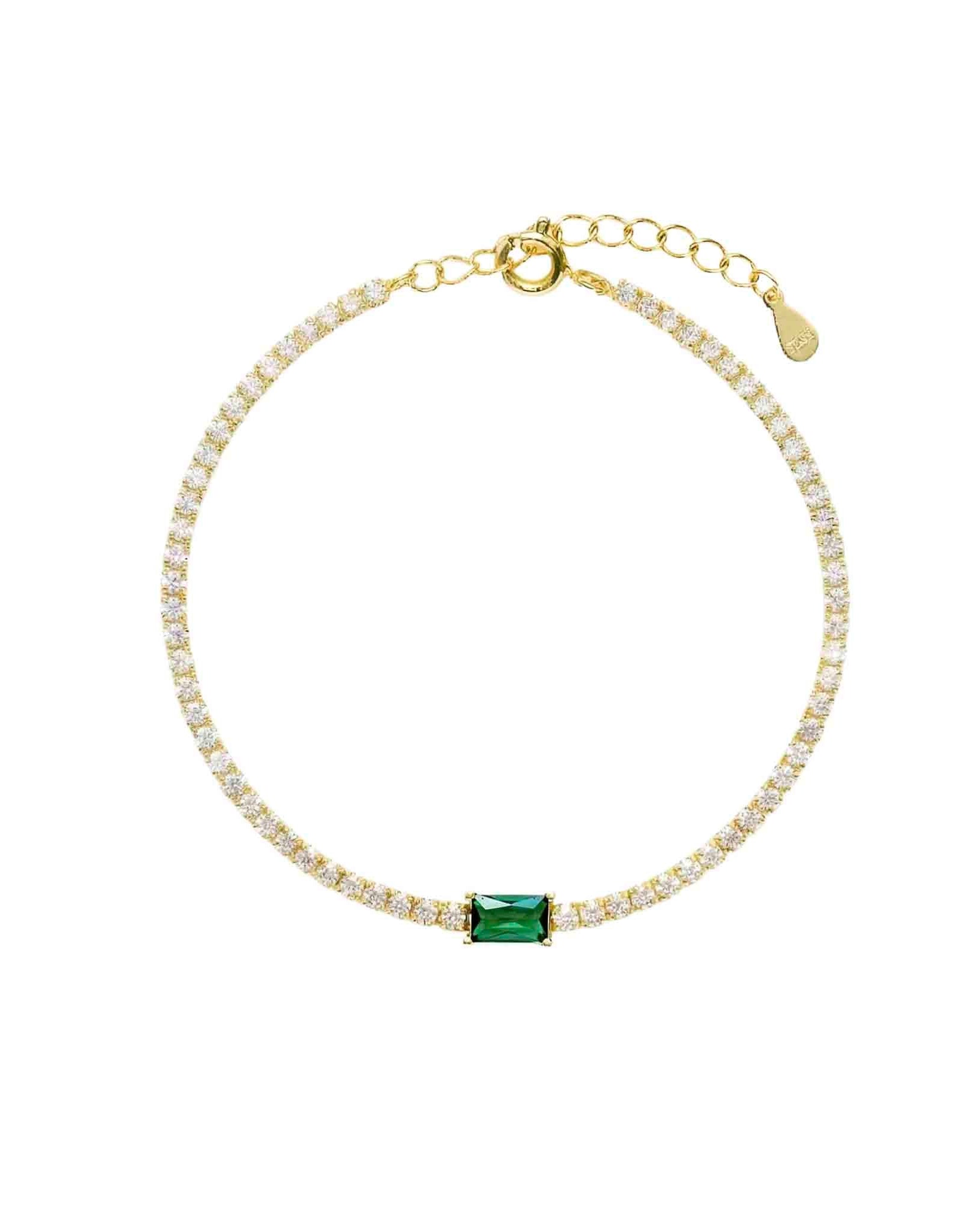 Gold bracelet with a green gemstone on a white background