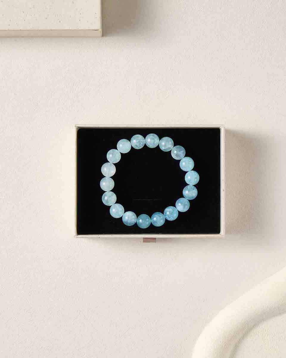 Still life photography of Choodo 11mm natural Aquamarine gemstone beaded bracelet displayed in a premium black foam jewelry gift box, highlighting the stunning natural gradient color in each bead.