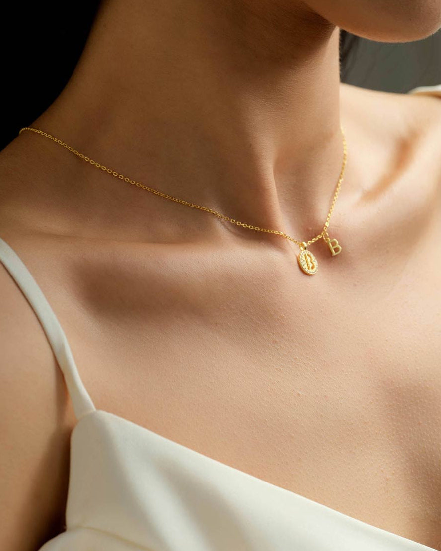 Female model wearing Choodo gold plated sterling silver dual 'B' letter pendant necklace on the collarbone, personalized jewelry