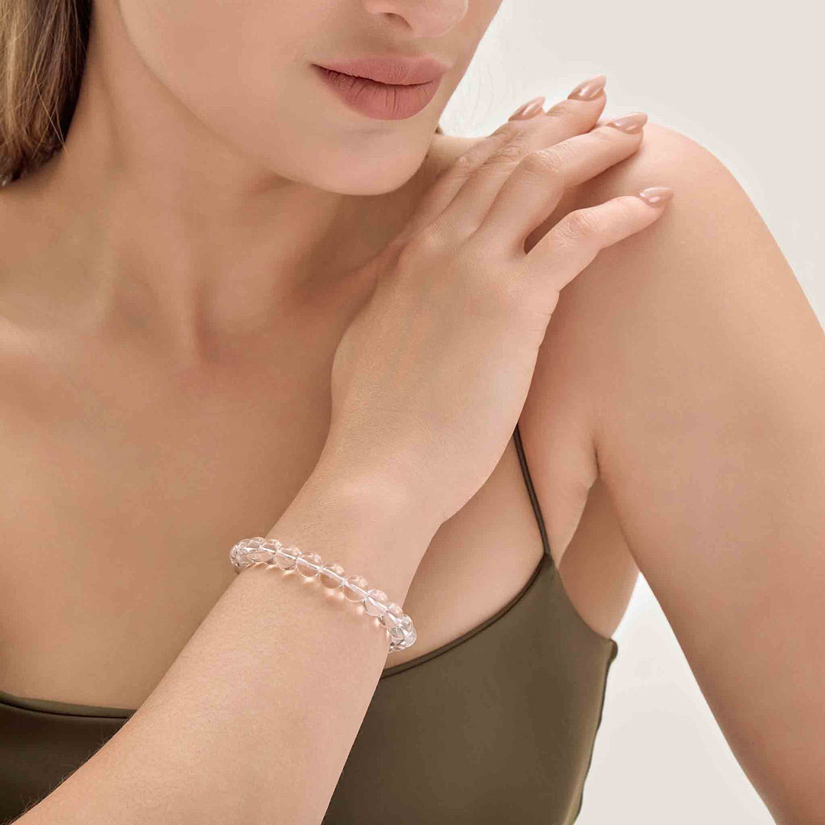 Choodo minimalist natural Light Clear Quartz crystal bracelet styled on a model's wrist, paired with a luxurious emerald green silk dress, premium organic aesthetic.