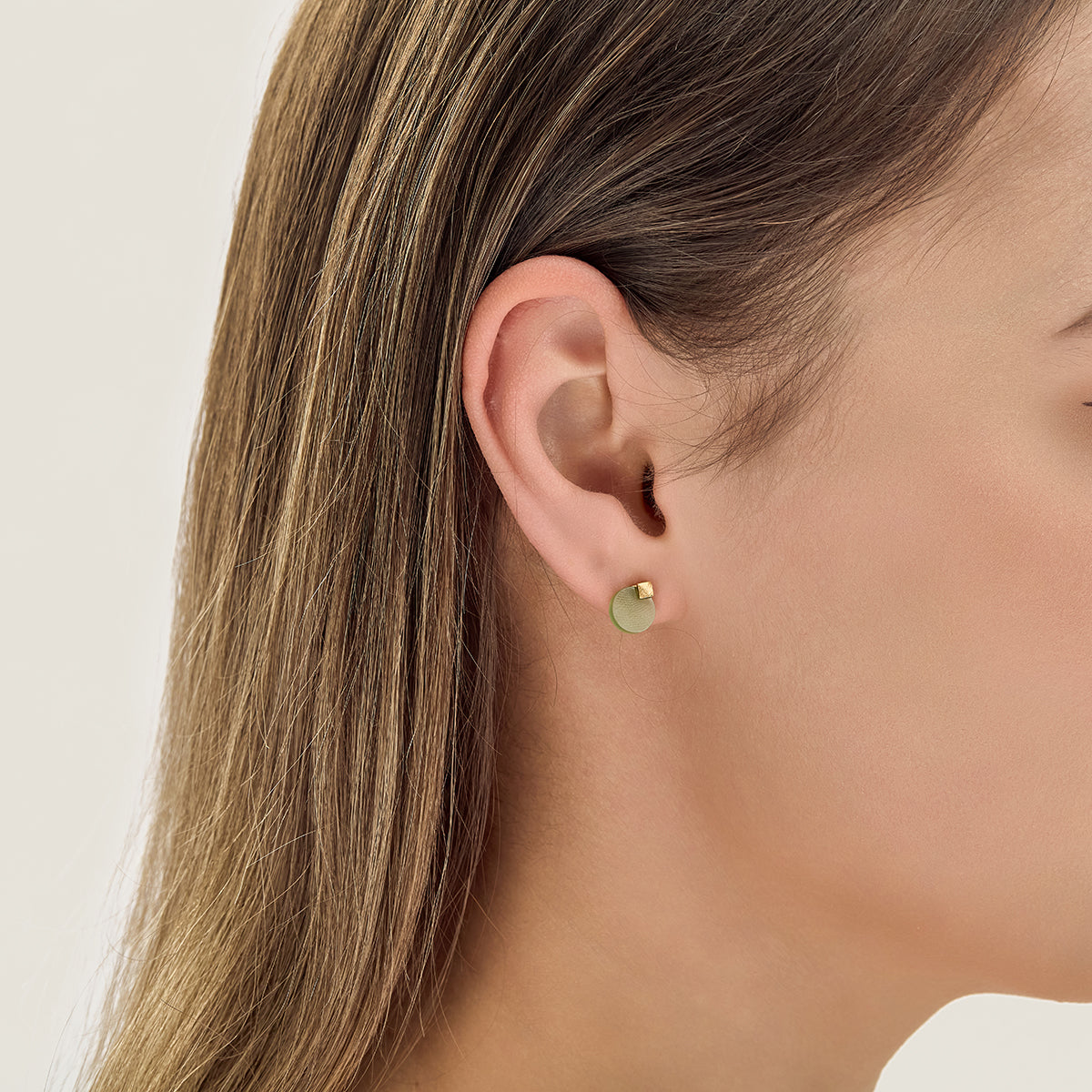 Choodo minimalist natural green Jade stud earrings styled on a model's ear, close up photo for an intellectual fashion look.