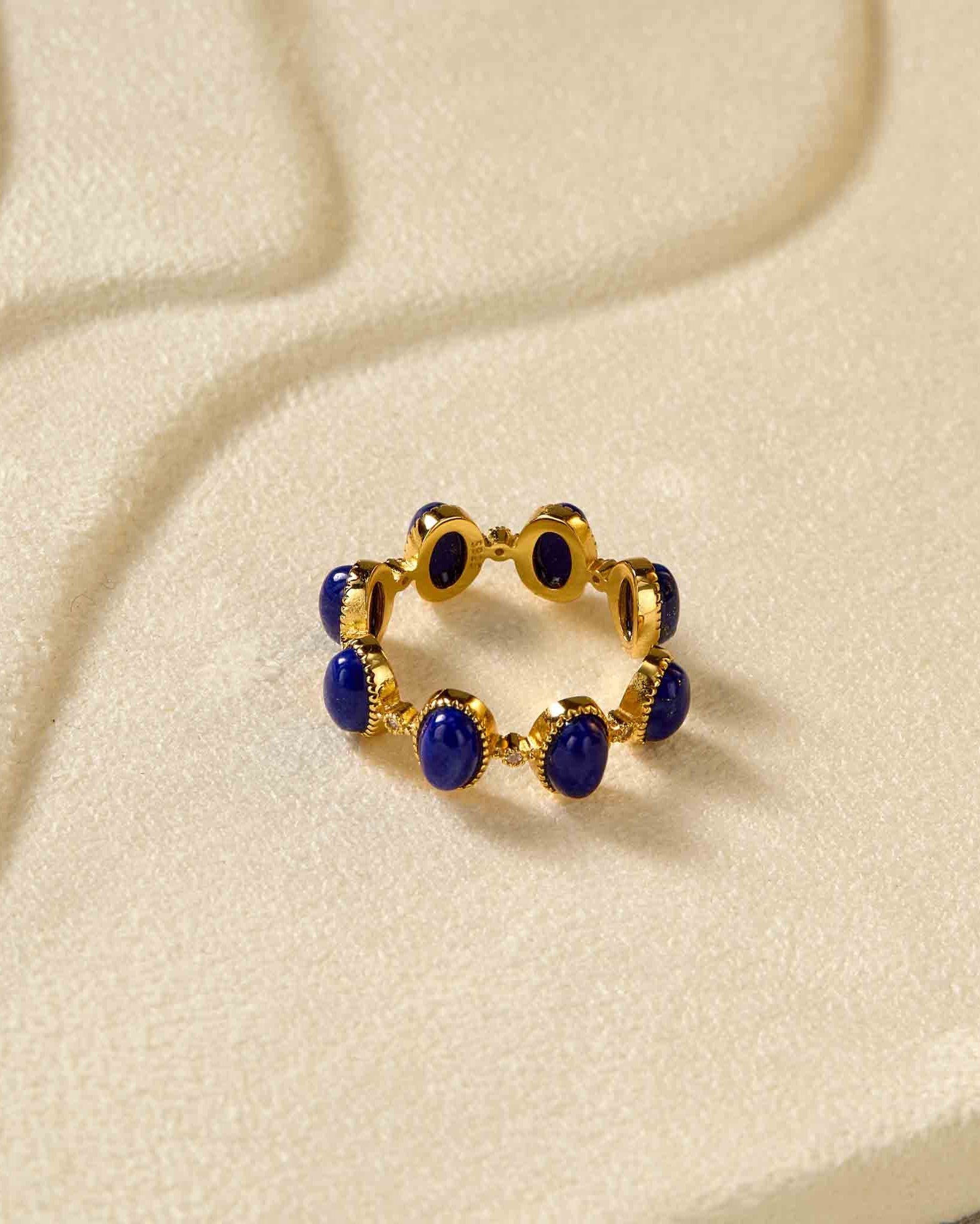 Gold ring with blue stones on a beige fabric background