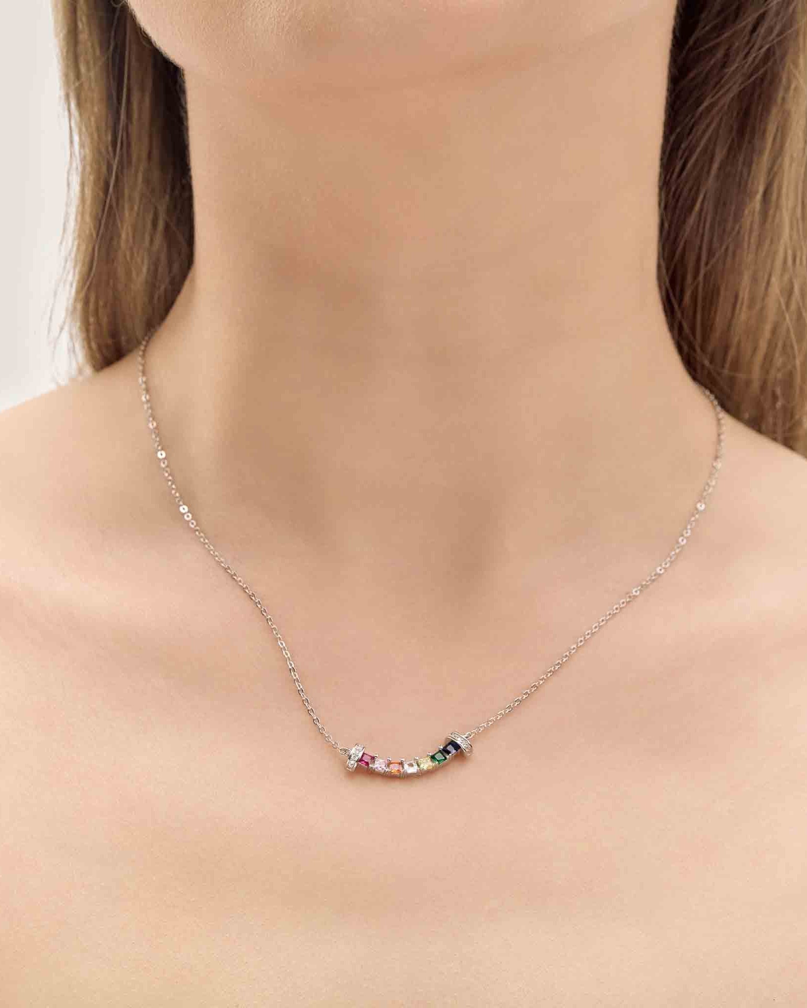 Necklace with colorful beads on a person's neck against a neutral background