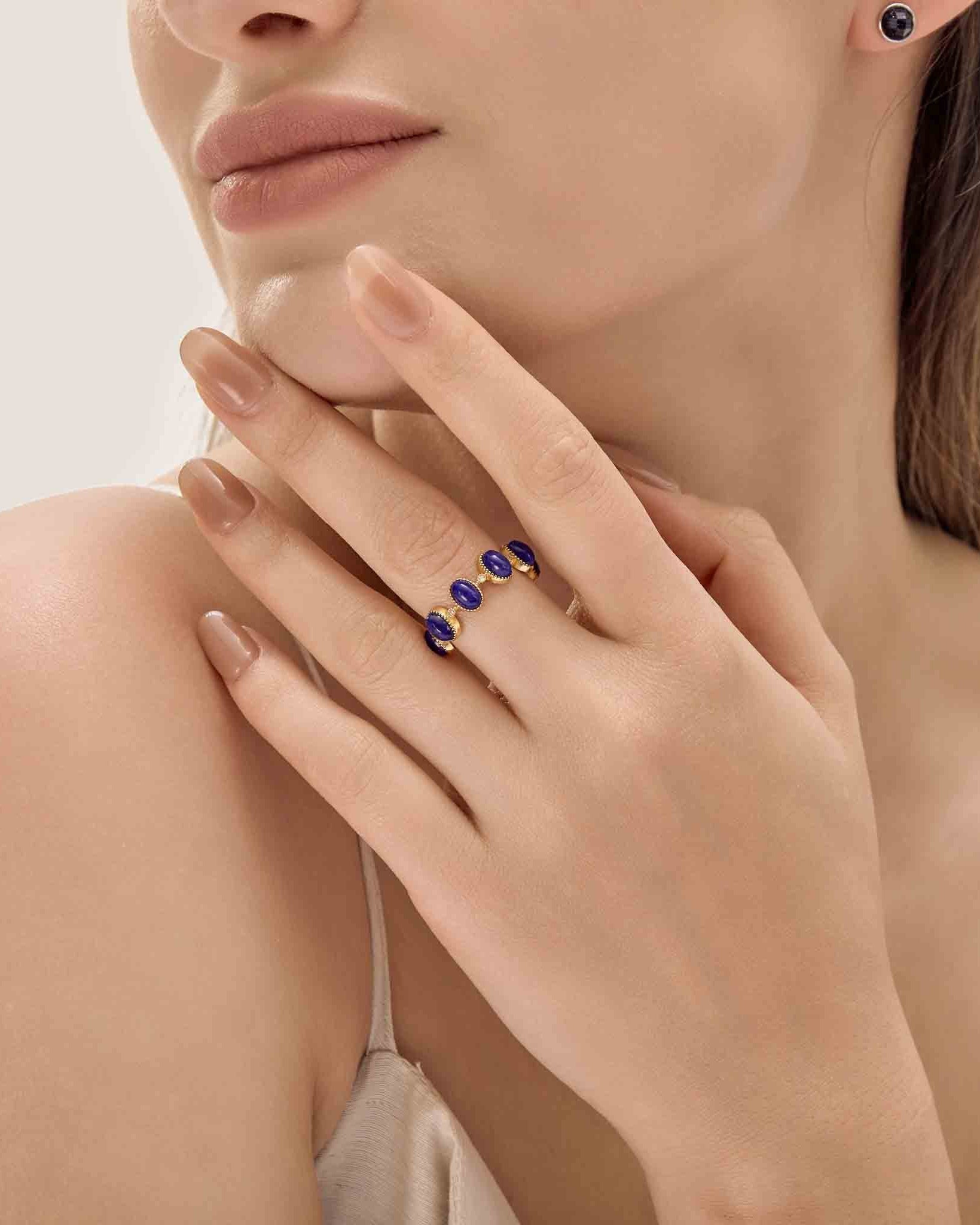 Woman wearing a ring with blue stones on a neutral background
