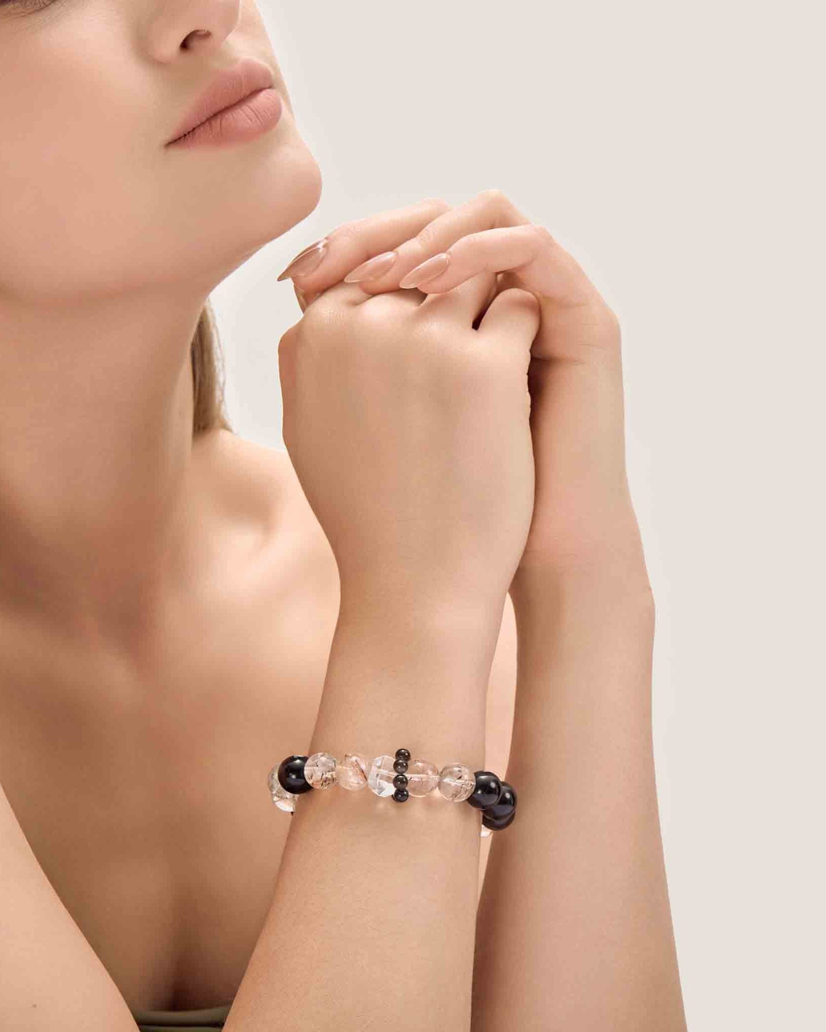 Woman wearing a bracelet with black and clear beads on a neutral background