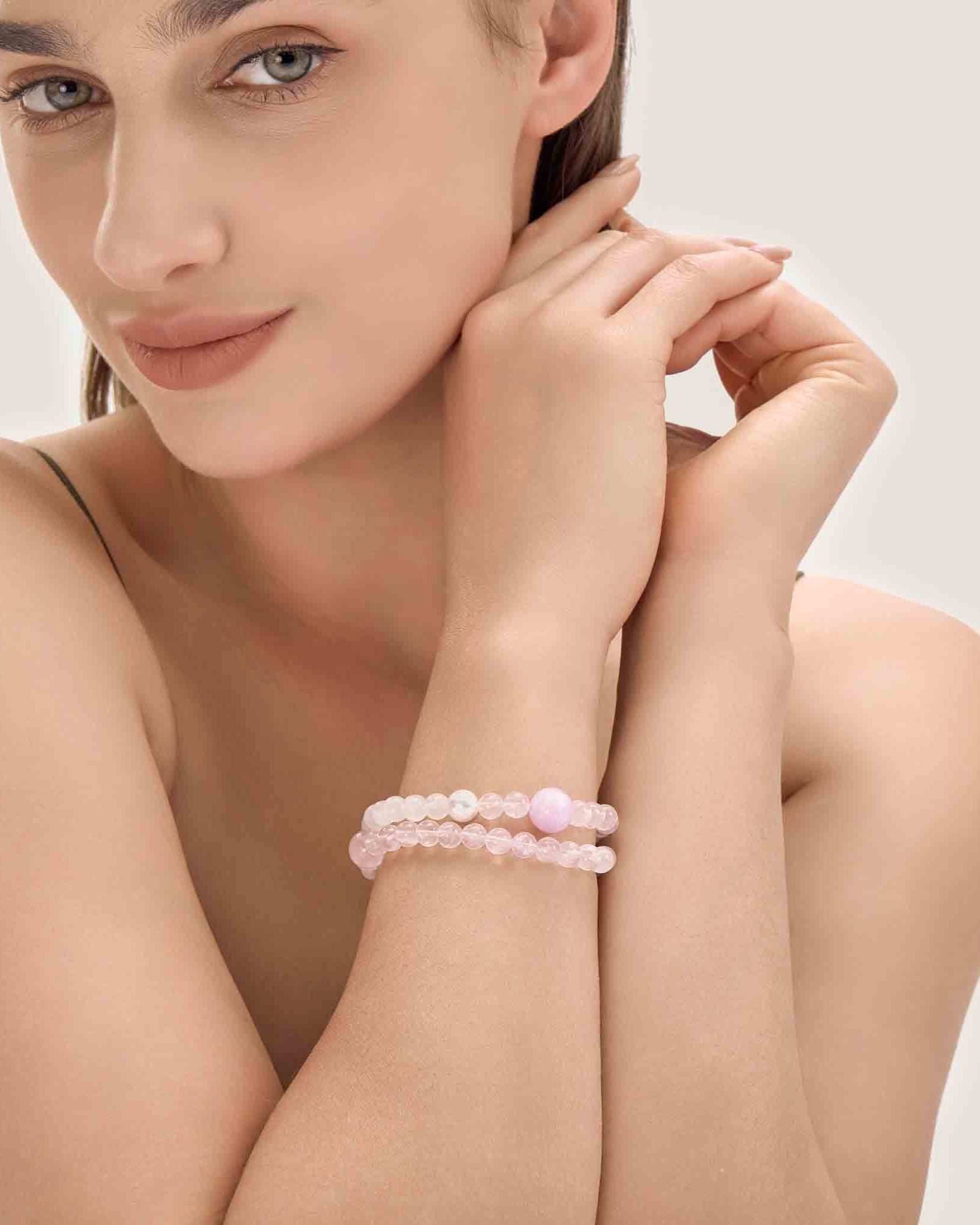 Woman wearing a pink bracelet on a plain background