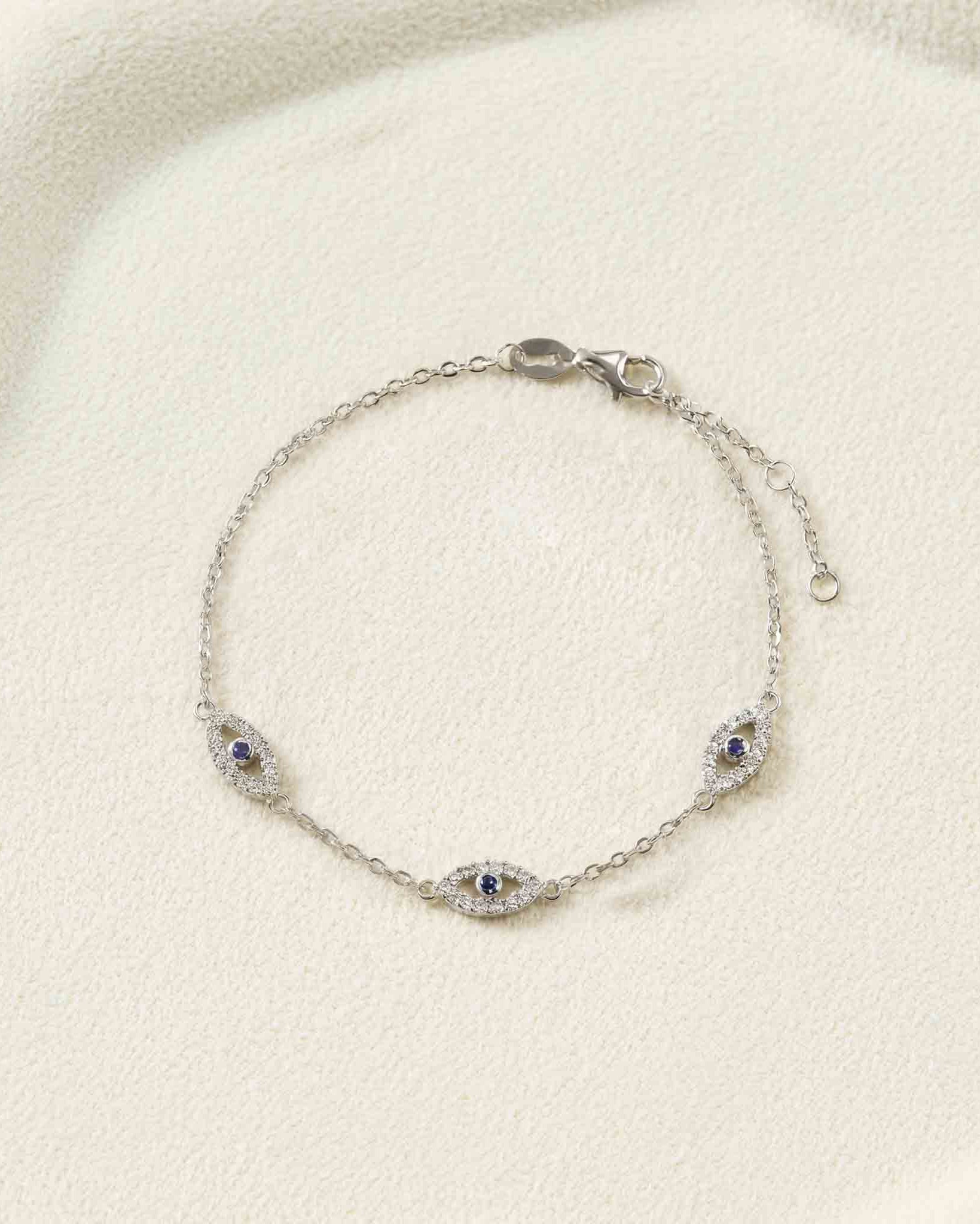 Silver bracelet with eye-shaped charms on a light beige fabric background