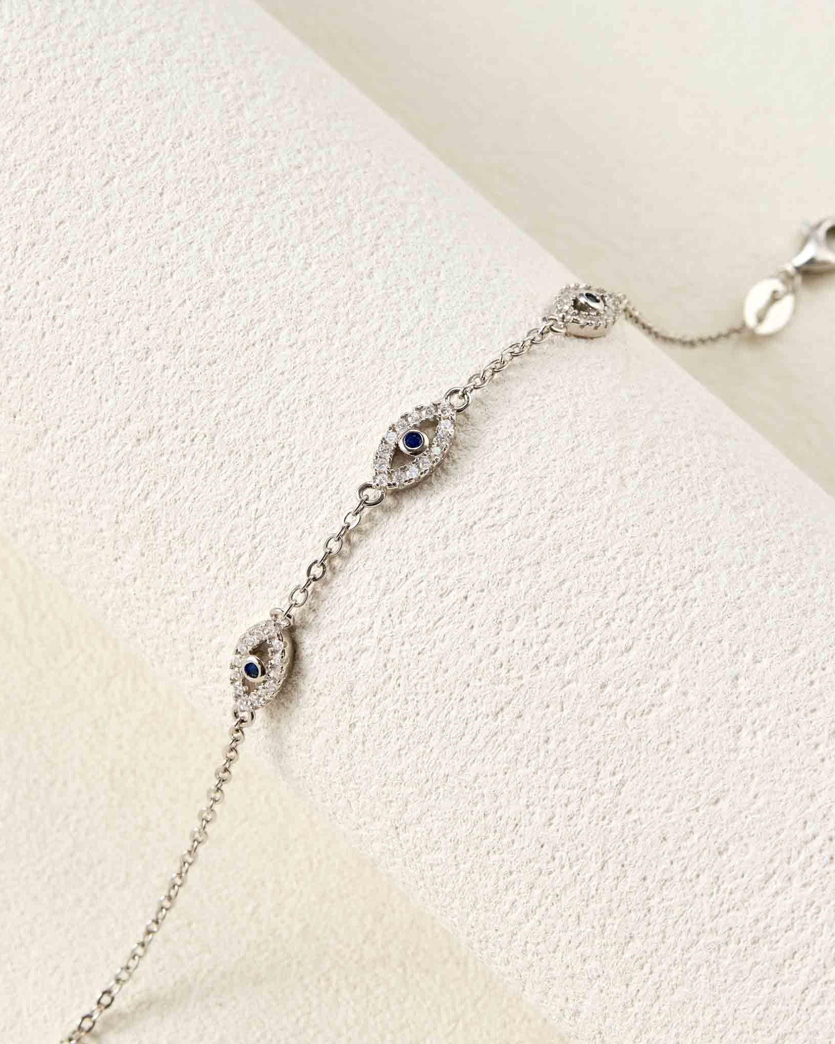 Silver bracelet with eye-shaped charms on a light background