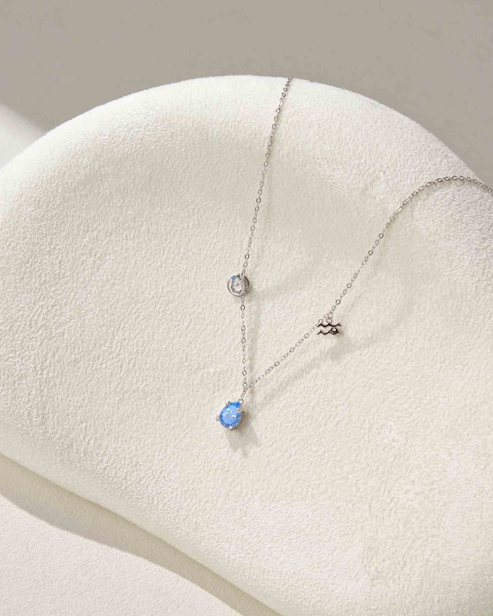 Necklace with a blue pendant on a white stand