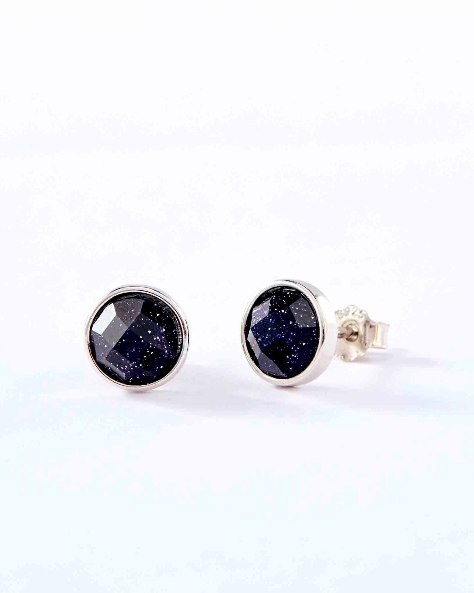 Pair of silver stud earrings with dark gemstones on a white background