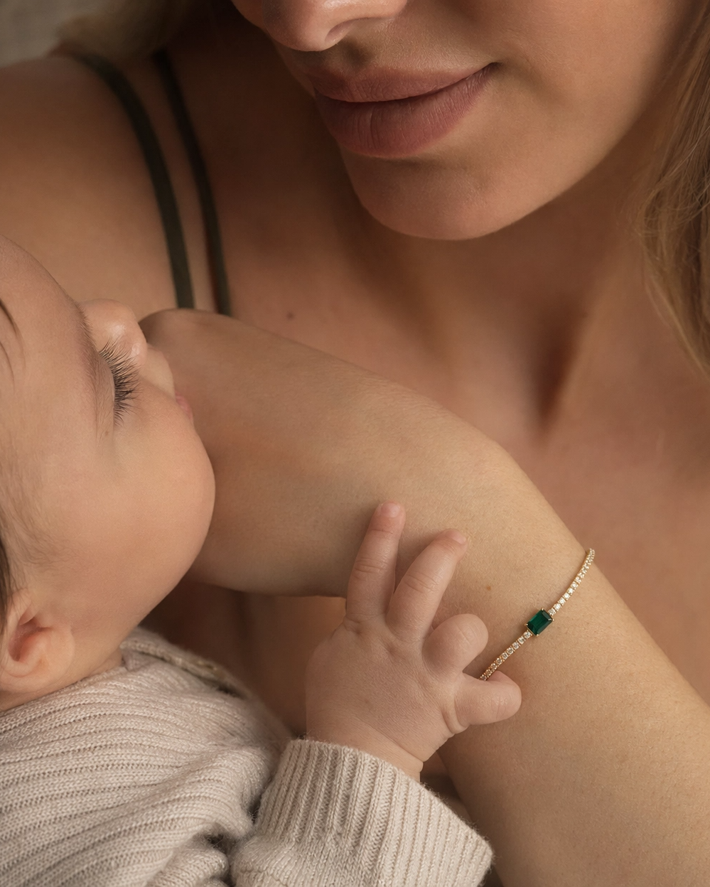Woman holding a baby close, with a focus on their arm and hand.