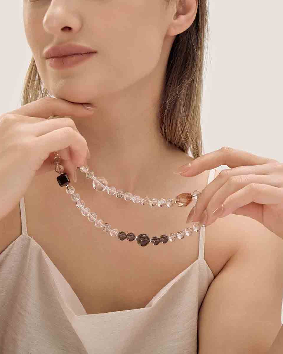 Choodo natural Golden Rutilated Quartz double wrap bracelet held in a model's hands to showcase length, bathed in a warm cozy candlelight aesthetic lighting