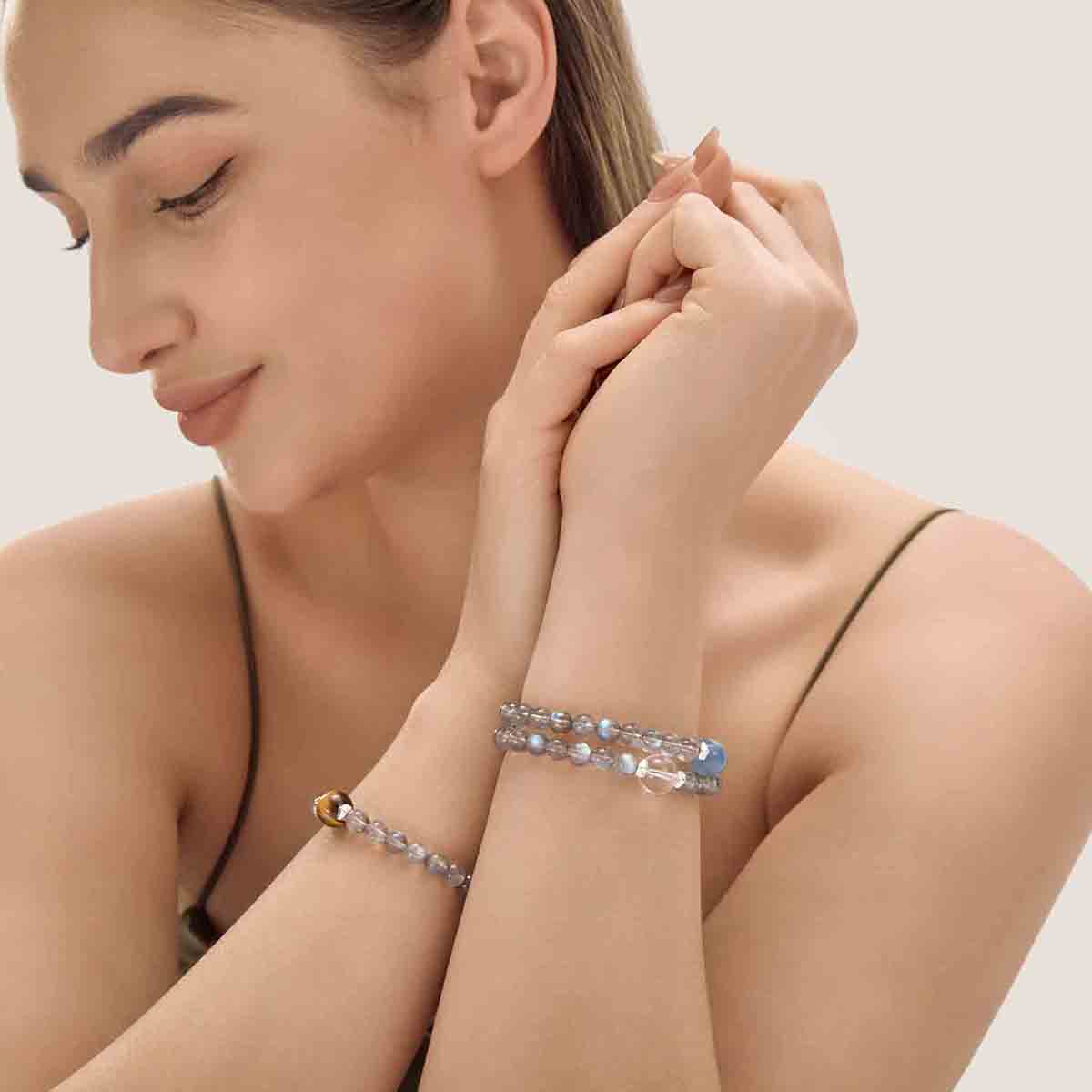 Choodo Orbit Collection Crystal Set D stacked on a model's wrist wearing a luxurious emerald green silk dress, high-contrast premium luxury fashion jewelry.