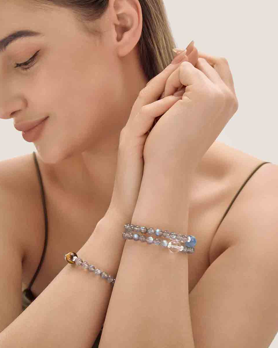 Choodo Orbit Collection Crystal Set D stacked on a model's wrist wearing a luxurious emerald green silk dress, high-contrast premium luxury fashion jewelry.